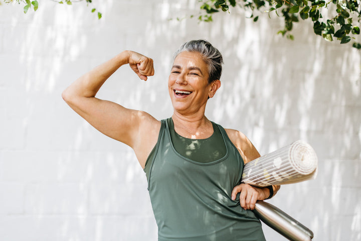 Ältere Frau zeigt ihren Bizeps und feiert ihre Fitness-Erfolge.
