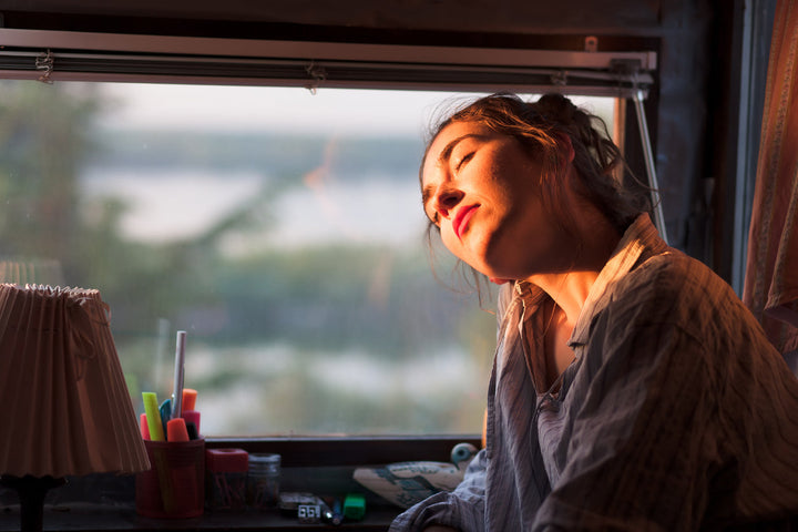 Junge Frau die morgens neben Ihrem Fenster Sonne tankt.