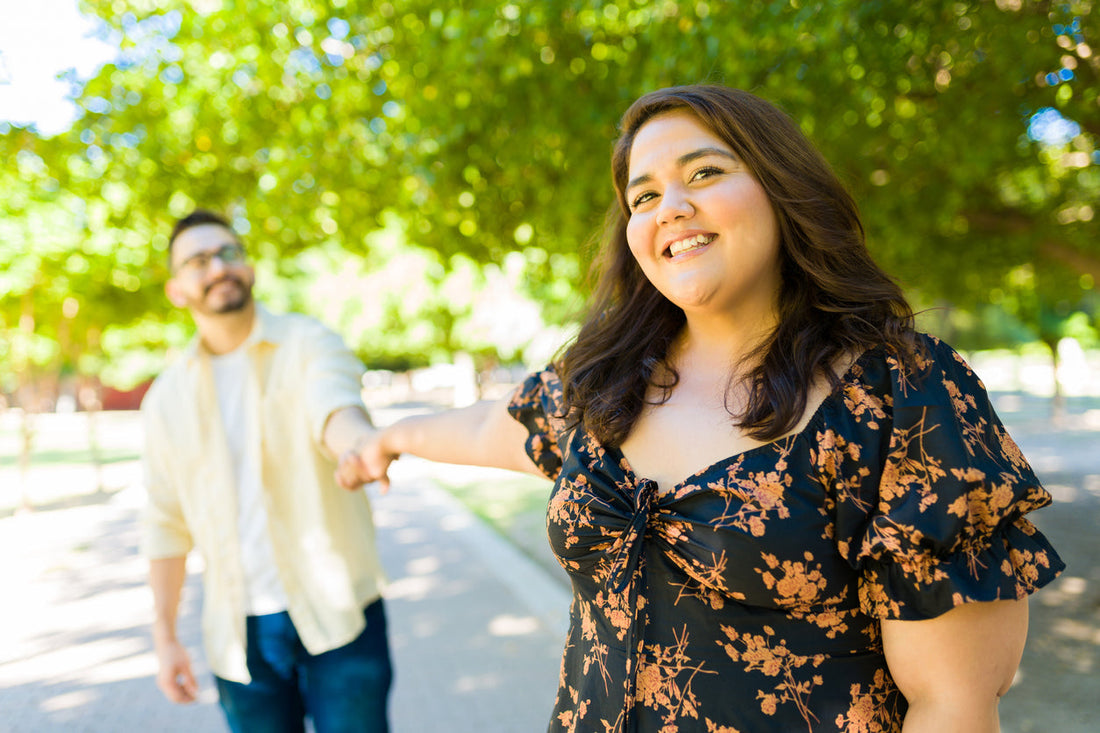 Aufgeregte Frau, die fröhlich aussieht, während sie Händchen hält und Spaß bei einem Date mit ihrem Freund hat.
