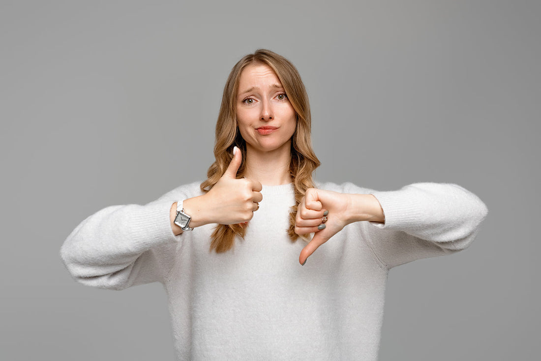 Eine Frau mit blonden Haaren hält vor sich beide Arme hoch und zeigt einen Daumen hoch und einen Daumen runter.