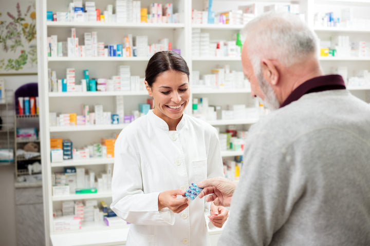 Freudestrahlende Apothekerin übergibt Medikamente an älteren männlichen Kunden