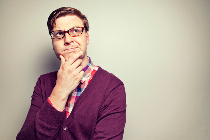 Mann mit Brille und violetter Weste blickt zweifelnd nach oben.