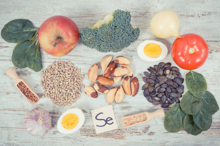 Tisch mit Zutaten wie Paranüsse, Tomaten, Ei, Knoblauch, Sonnenblumenkerne, Zwiebel, Brokkoli und Apfel.