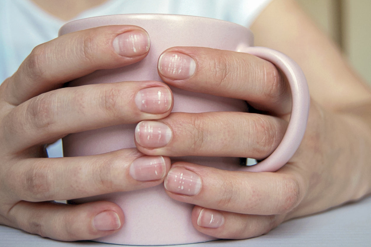 Damenhände liegen auf dem Tisch und umgreifen eine rosarote-Tasse.
